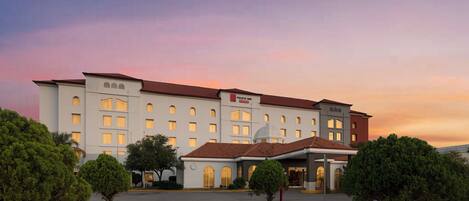 A hotel with a central courtyard, multiple entry points, and a prominent sign.