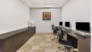 A conference room with a long table, four chairs, a dark wooden cabinet, and three computer monitors. - Fiesta Inn Express Nuevo Laredo (Nuevo Laredo)