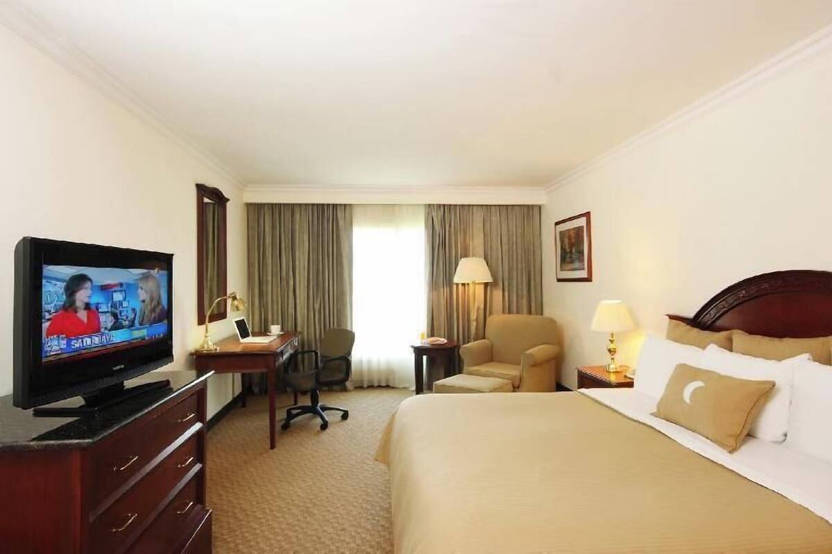Une chambre d’hôtel comprenant un lit, un bureau avec une chaise, une télévision et une lampe.