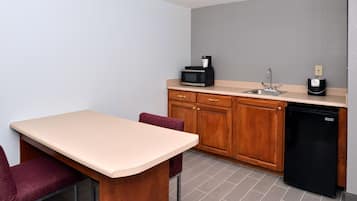Una cocina compacta con un armario de madera, un refrigerador negro, un microondas y un lavamanos.