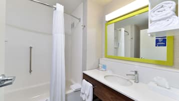 Un baño moderno con bañera, ducha, tocador con lavabo y espejo con marco amarillo.