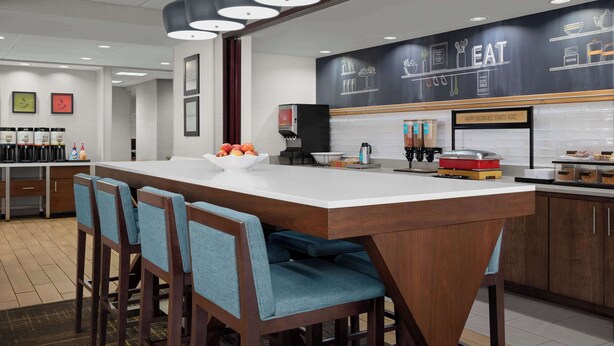 A modern kitchen with a large island, bar stools, and a chalkboard wall with kitchen utensils. - Hampton Inn Panama City Beach (Panama City Beach)