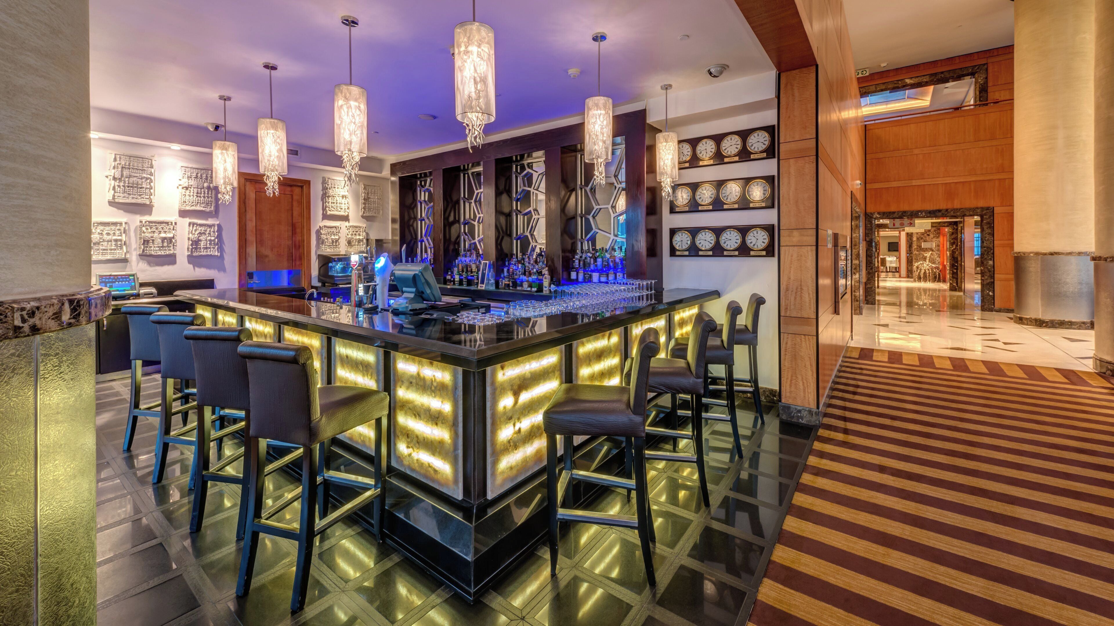 A modern bar area with a central island, bar stools, and decorative lighting.