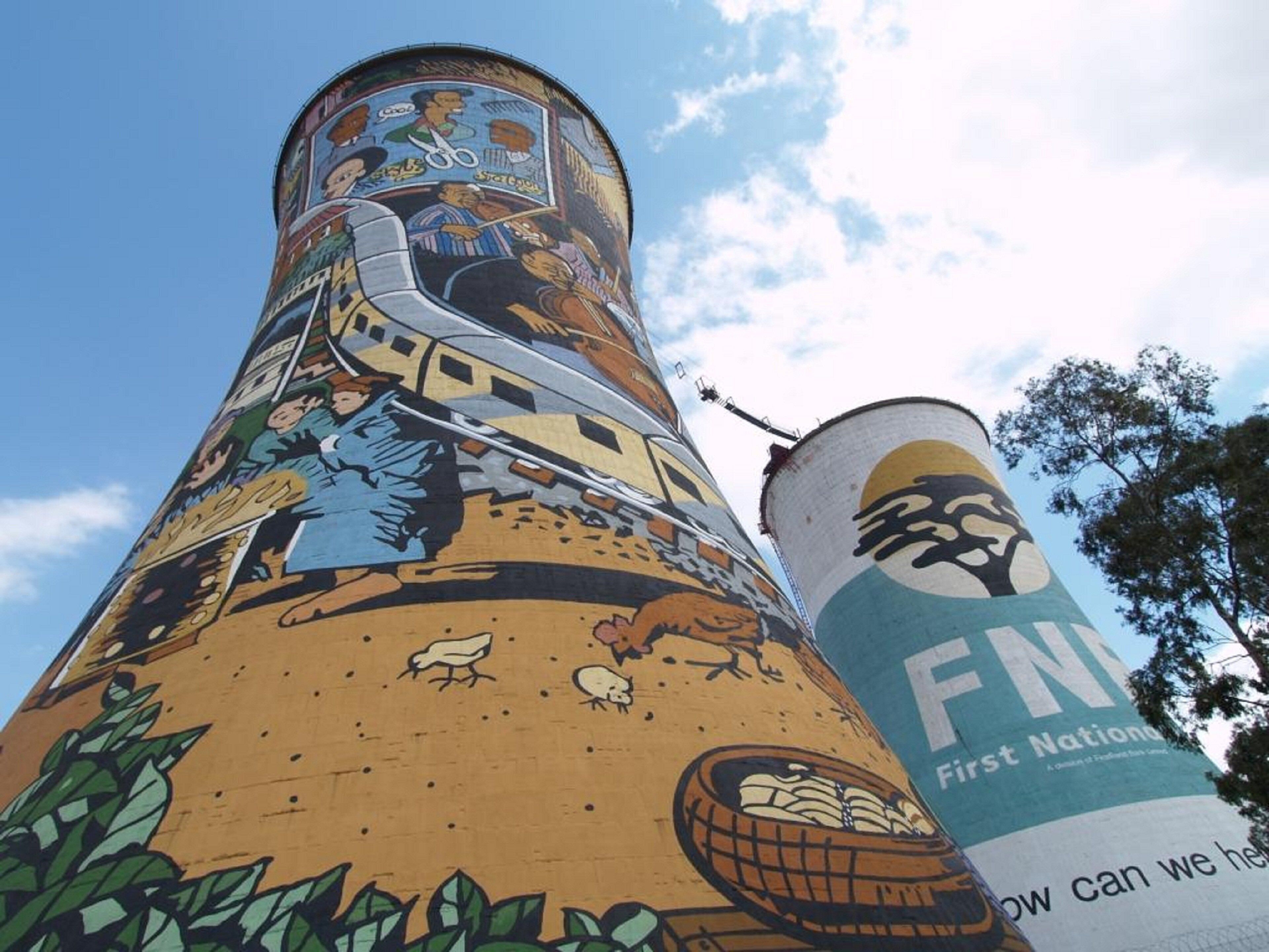 A cylindrical structure with a mural, partially visible text, and a clear sky.