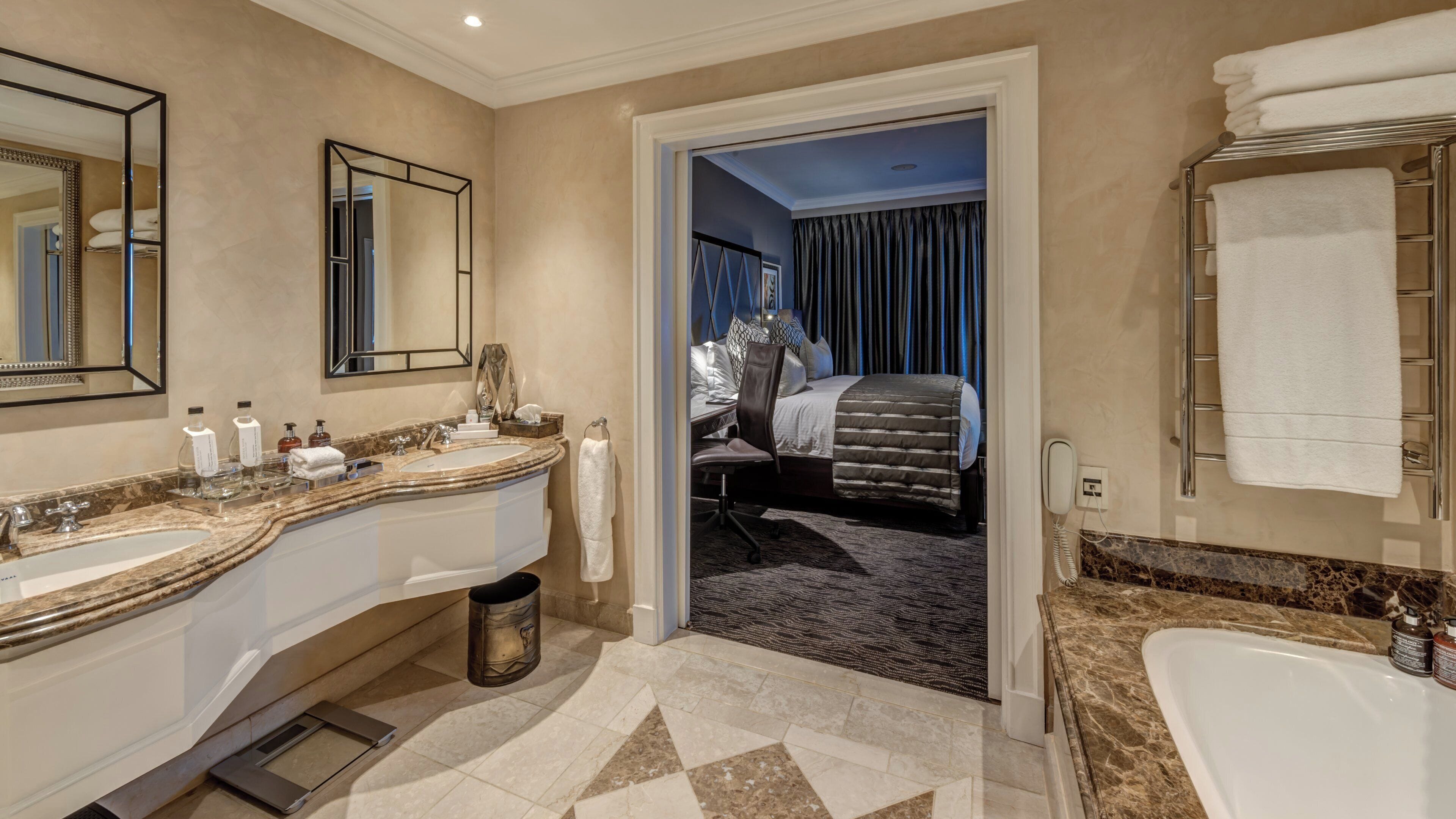 A hotel bathroom with a large sink, mirror, and bathtub.