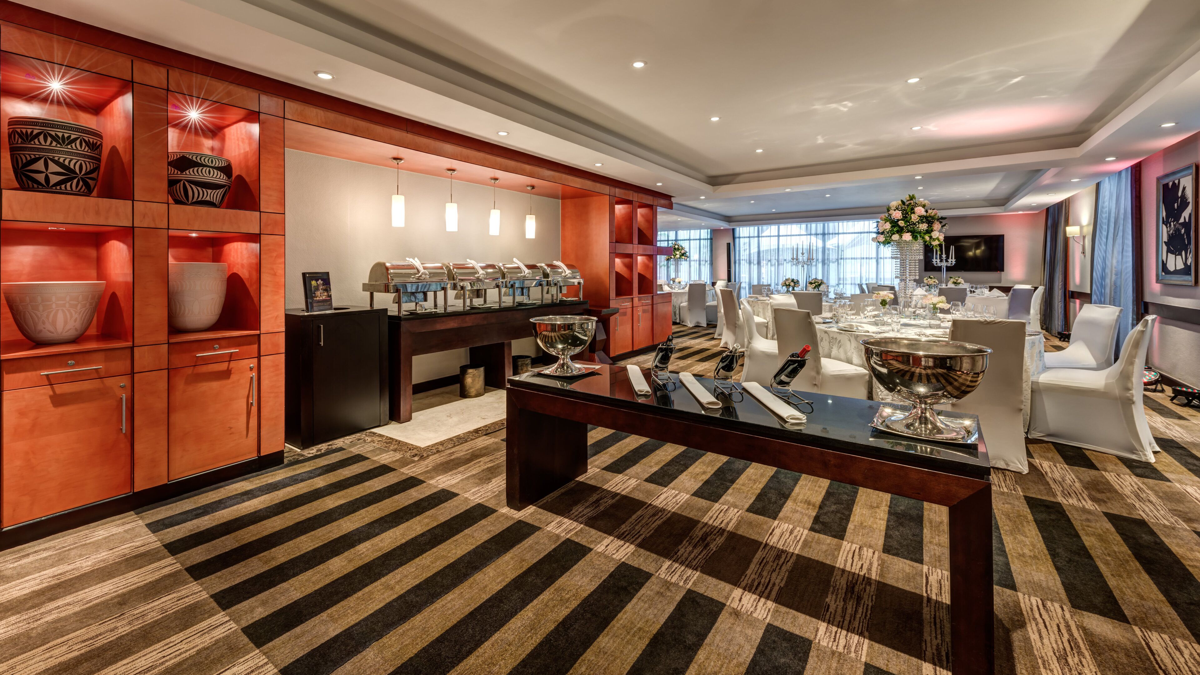 A hotel dining area with a central table, buffet, and seating.