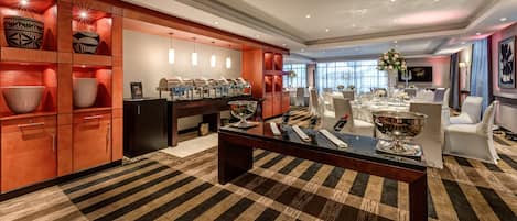 A hotel dining area with a central table, buffet, and seating.