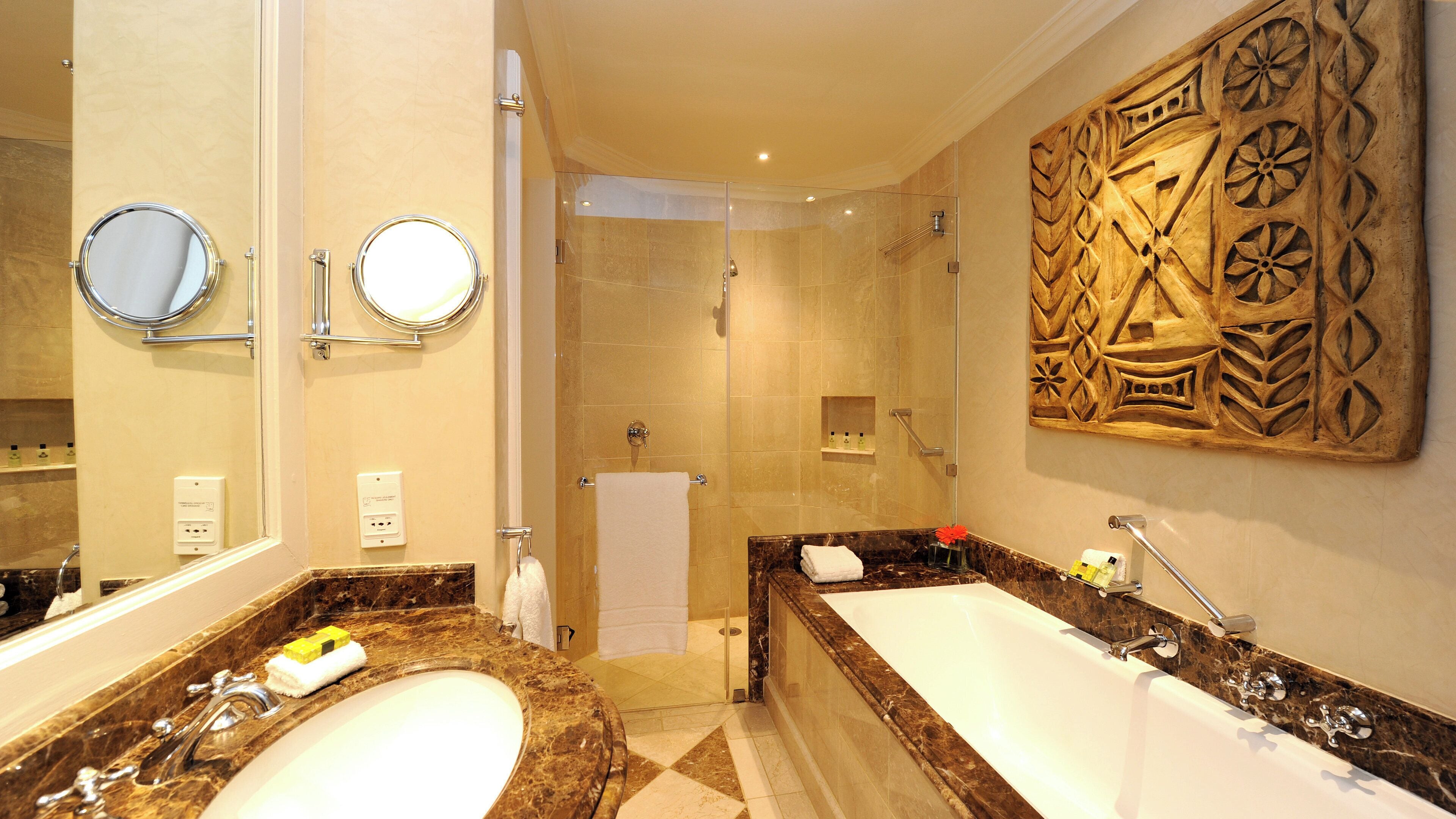 A bathroom with two sinks, a shower, and a large mirror.