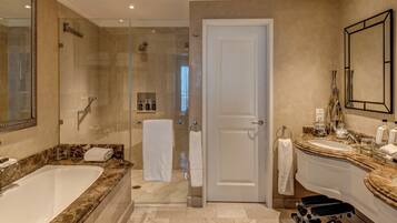 A modern bathroom with a large bathtub, a glass-enclosed shower, and a vanity with a marble countertop.