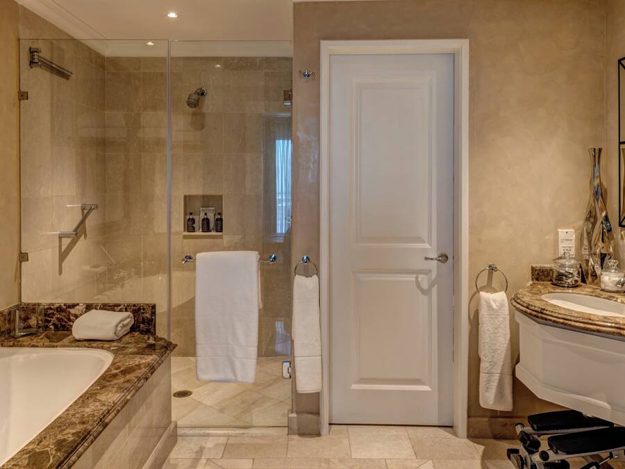 A modern bathroom with a large bathtub, a glass-enclosed shower, and a vanity with a marble countertop.