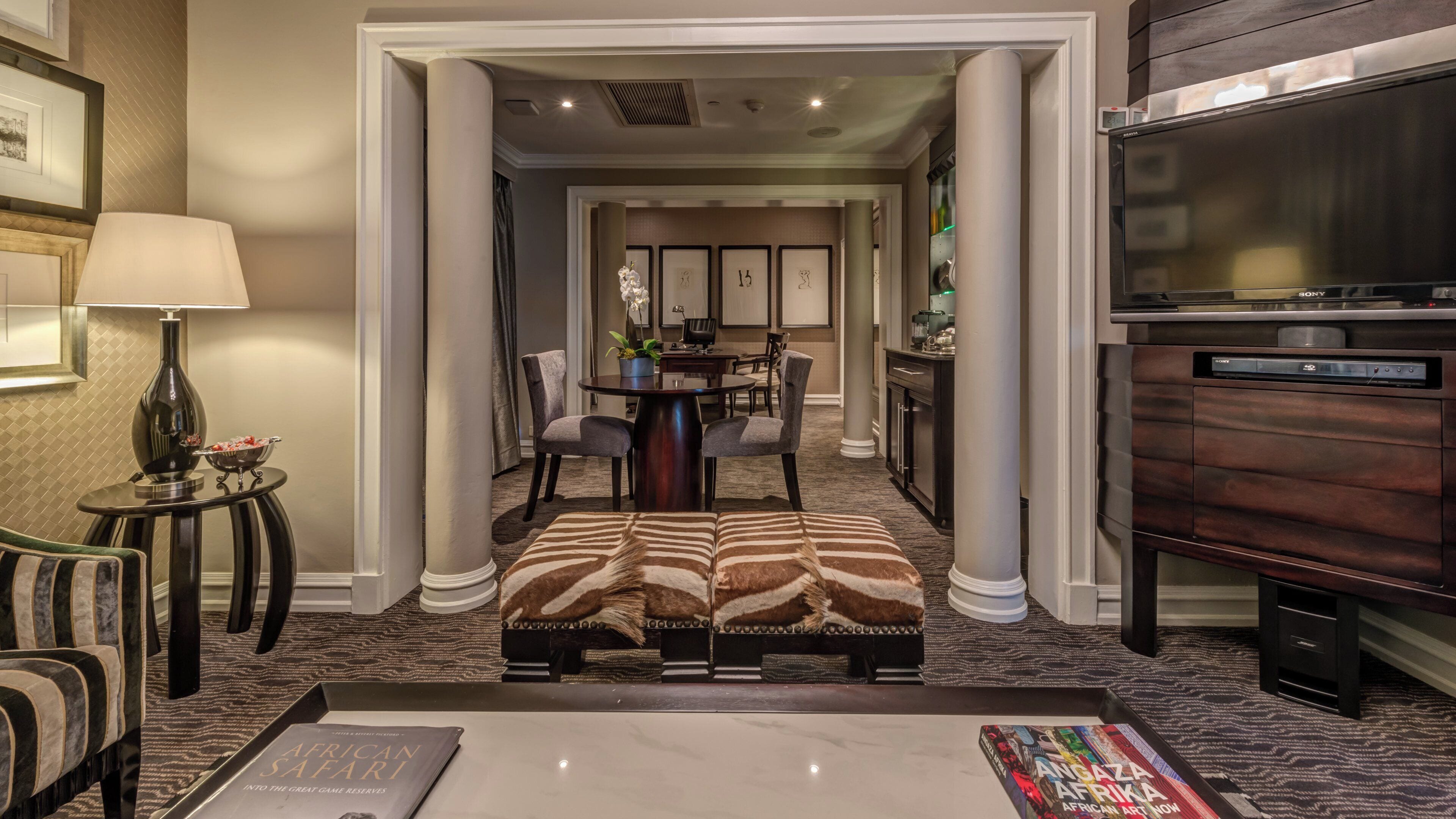 A hotel lobby with a dining area, a sofa, a lamp, and a Sony TV.