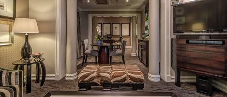 A hotel lobby with a dining area, a sofa, a lamp, and a Sony TV.