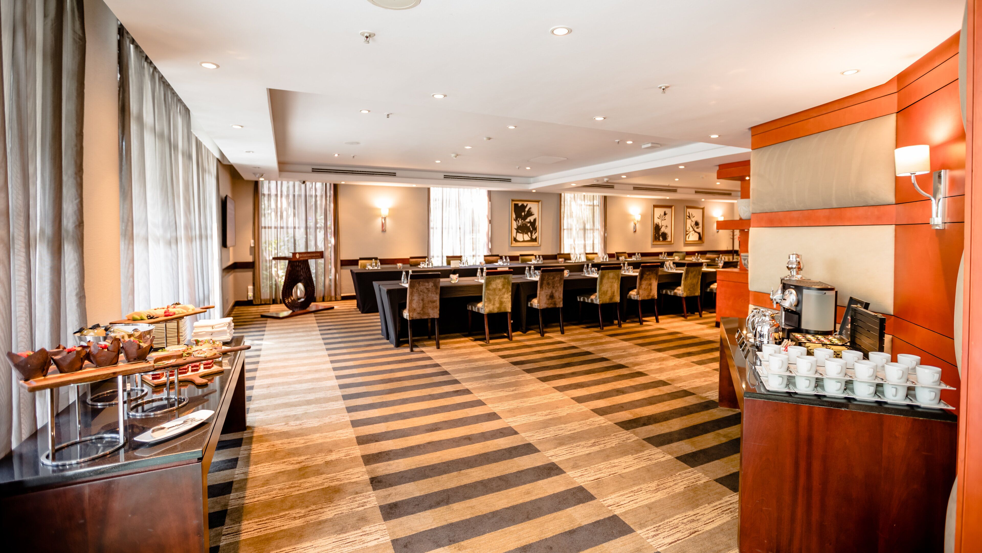 Un hall de hotel con una zona de bufé, varias mesas de comedor y una estación de café.