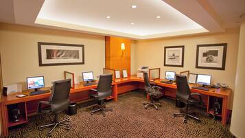 A conference room with four desks, each with a computer and chair, and framed pictures on the walls.