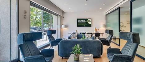 A modern lounge area with comfortable seating, a coffee table, and a television screen displaying a message.