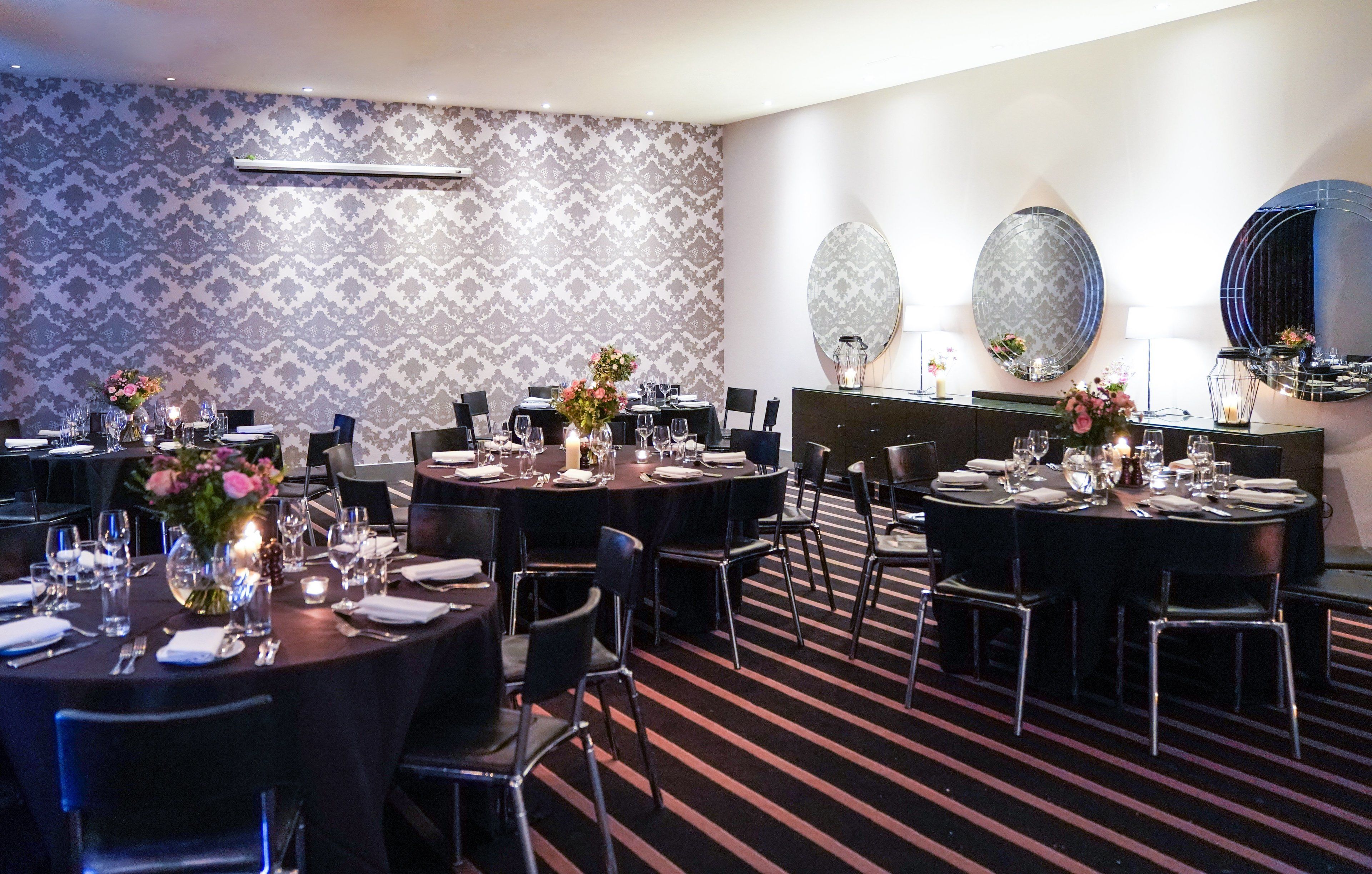 A dining area with round tables, black chairs, and floral centerpieces.