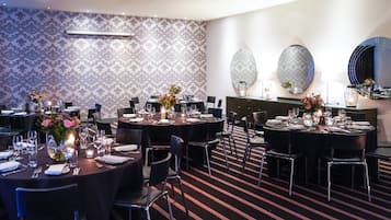 A dining area with round tables, black chairs, and floral centerpieces.