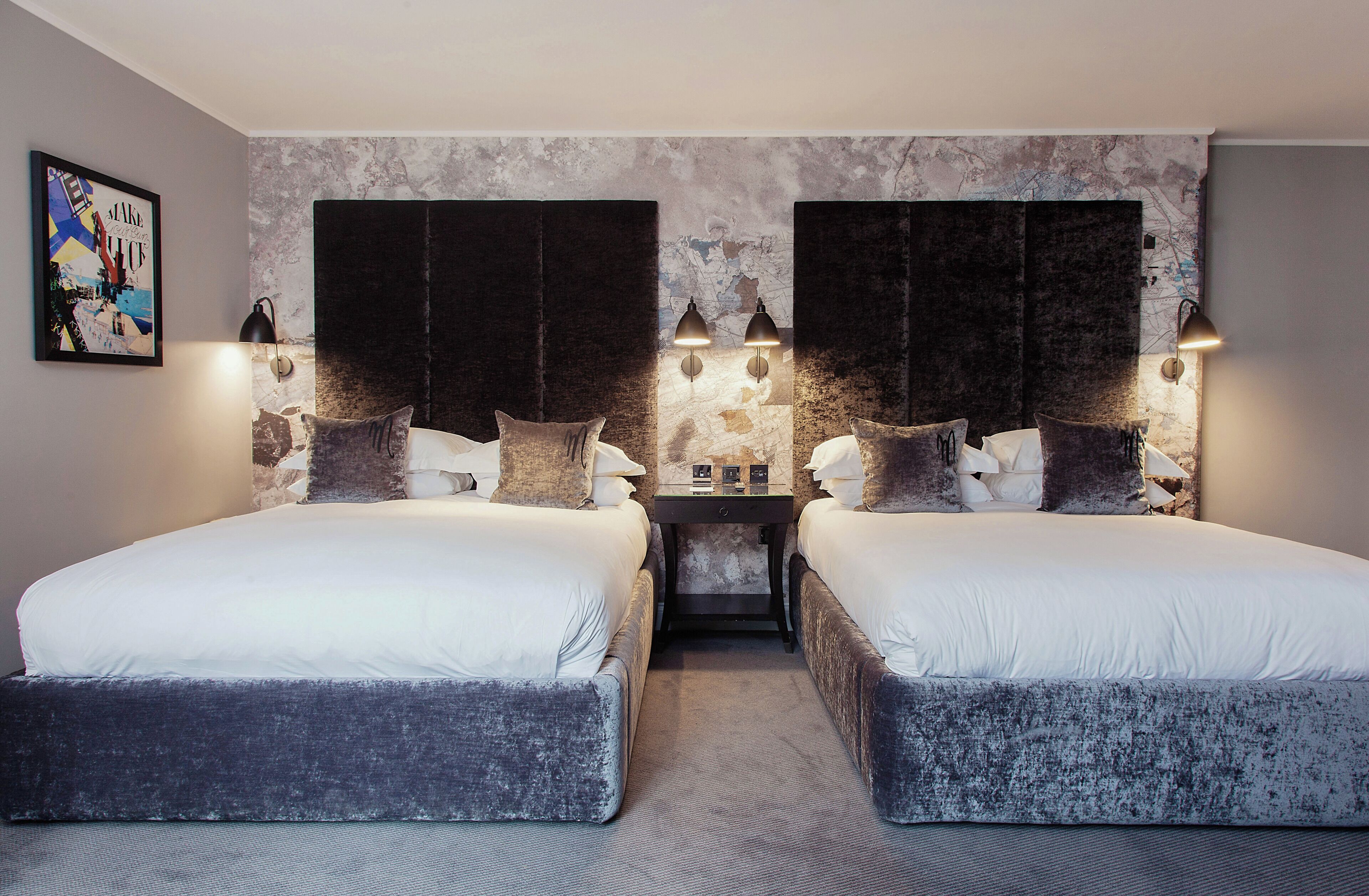 Une chambre double avec deux lits, une petite table et des lampes fixées au mur.