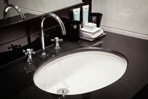 A modern bathroom with a black countertop, a white sink, and chrome fixtures.