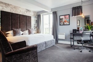 A modern hotel room with a large bed, a desk, and a chair.
