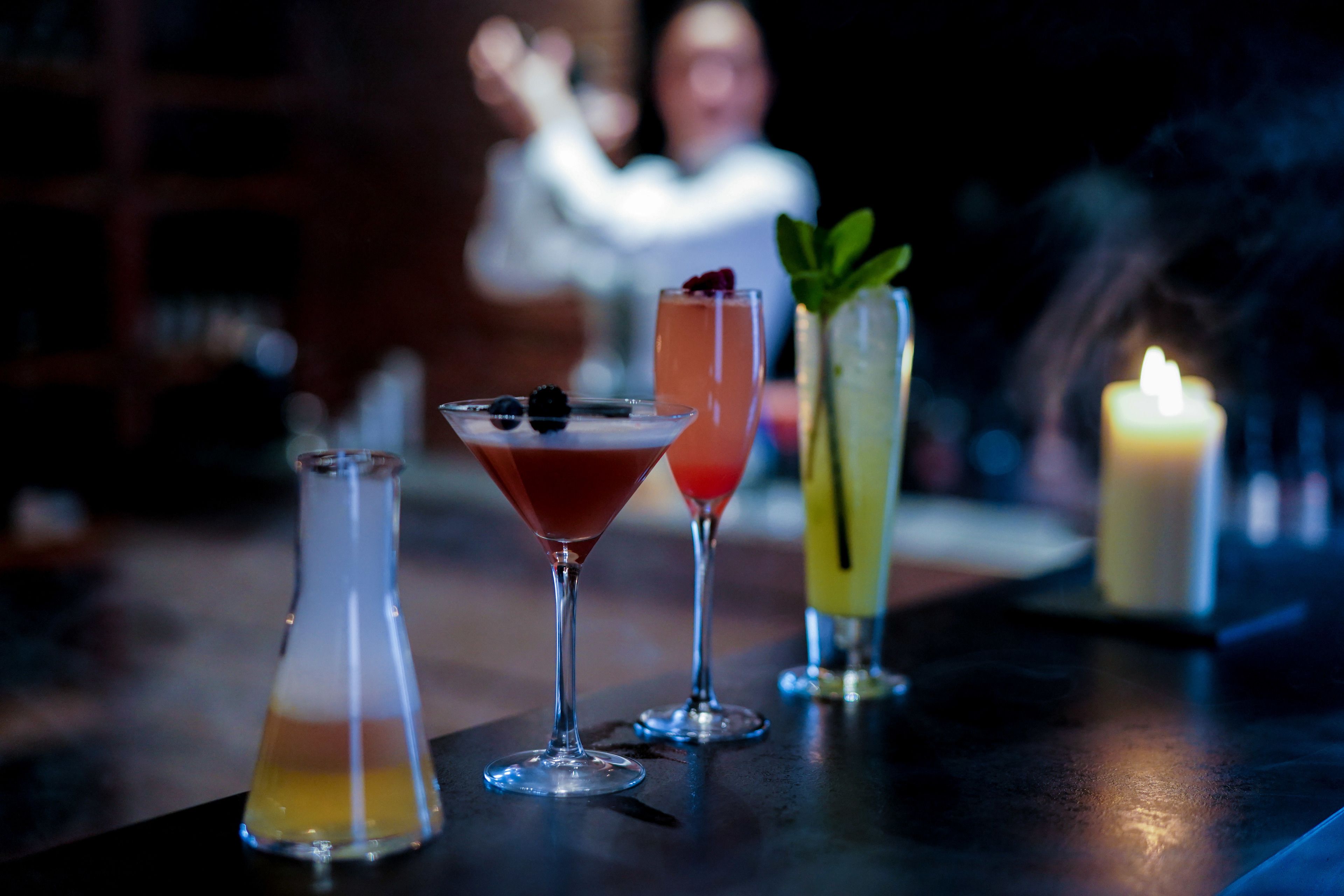 Un bar con tres cócteles y una vela.