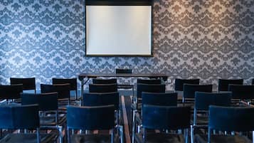 A conference room with a projector screen, rows of chairs, and patterned wallpaper.