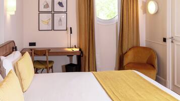 A hotel room with a bed, a desk, a chair, and a window with curtains.