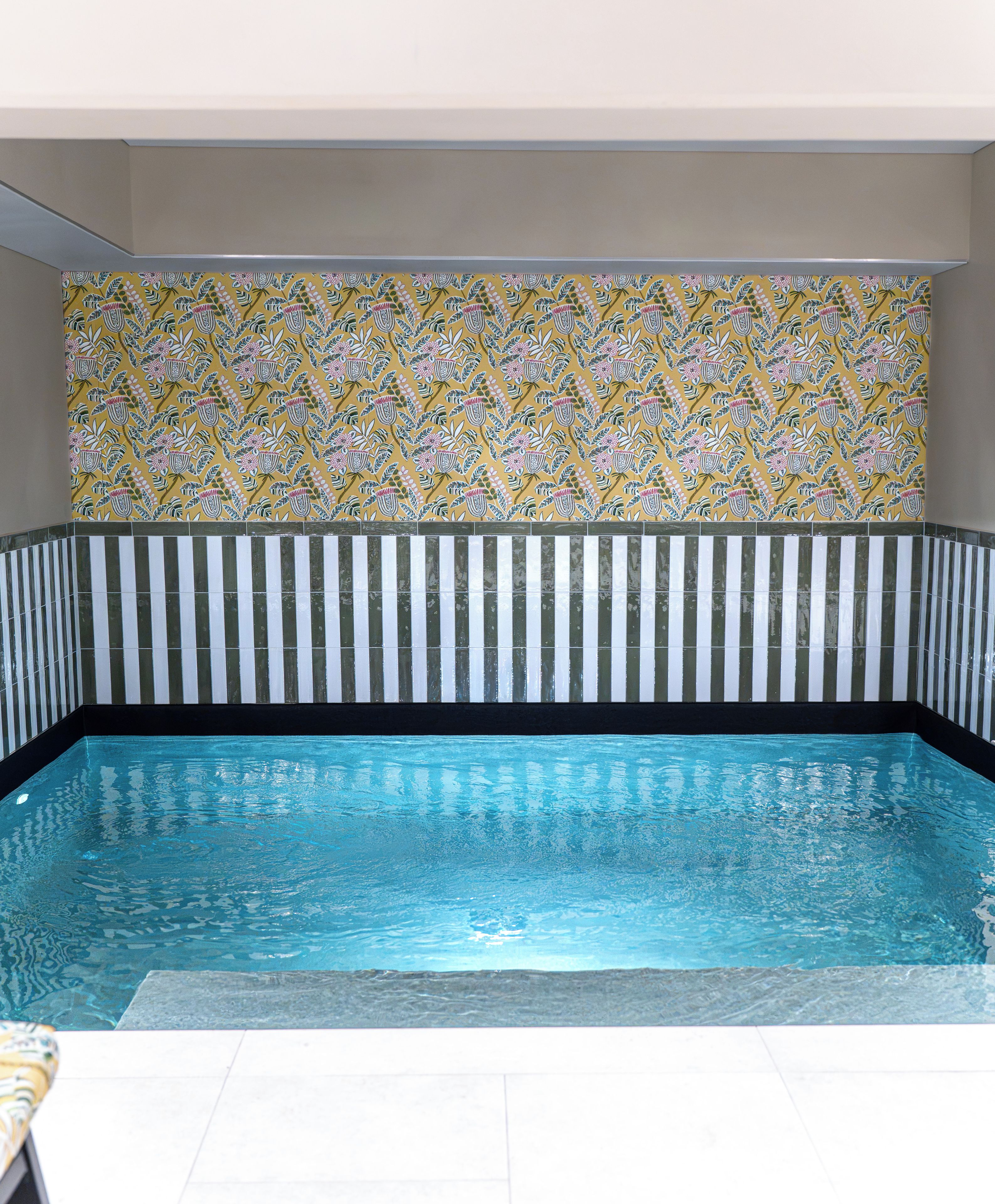 A swimming pool with a tiled wall featuring a floral pattern.