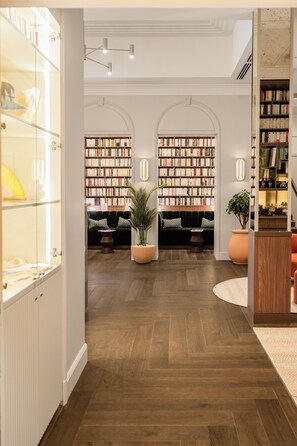 L’intérieur d’une bibliothèque, avec des étagères, des espaces de lecture et un plancher en bois.