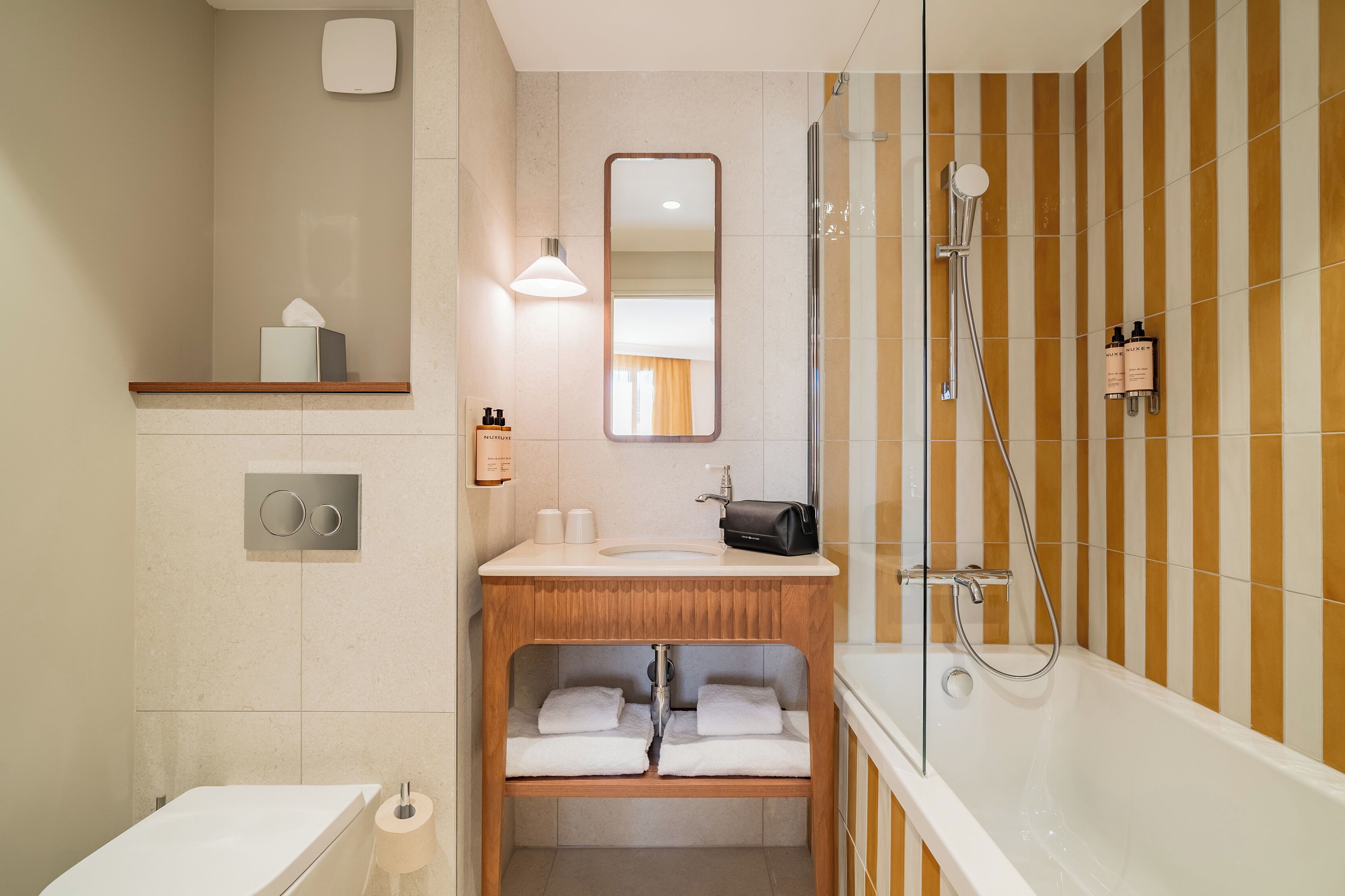 Ein modernes Badezimmer mit Dusche, Waschbecken, Spiegel und Handtuchhalter.