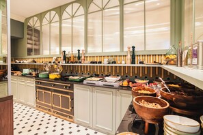 A kitchen with a buffet setup, featuring a variety of food items and utensils. - Hôtel Lepoussin (Cannes)