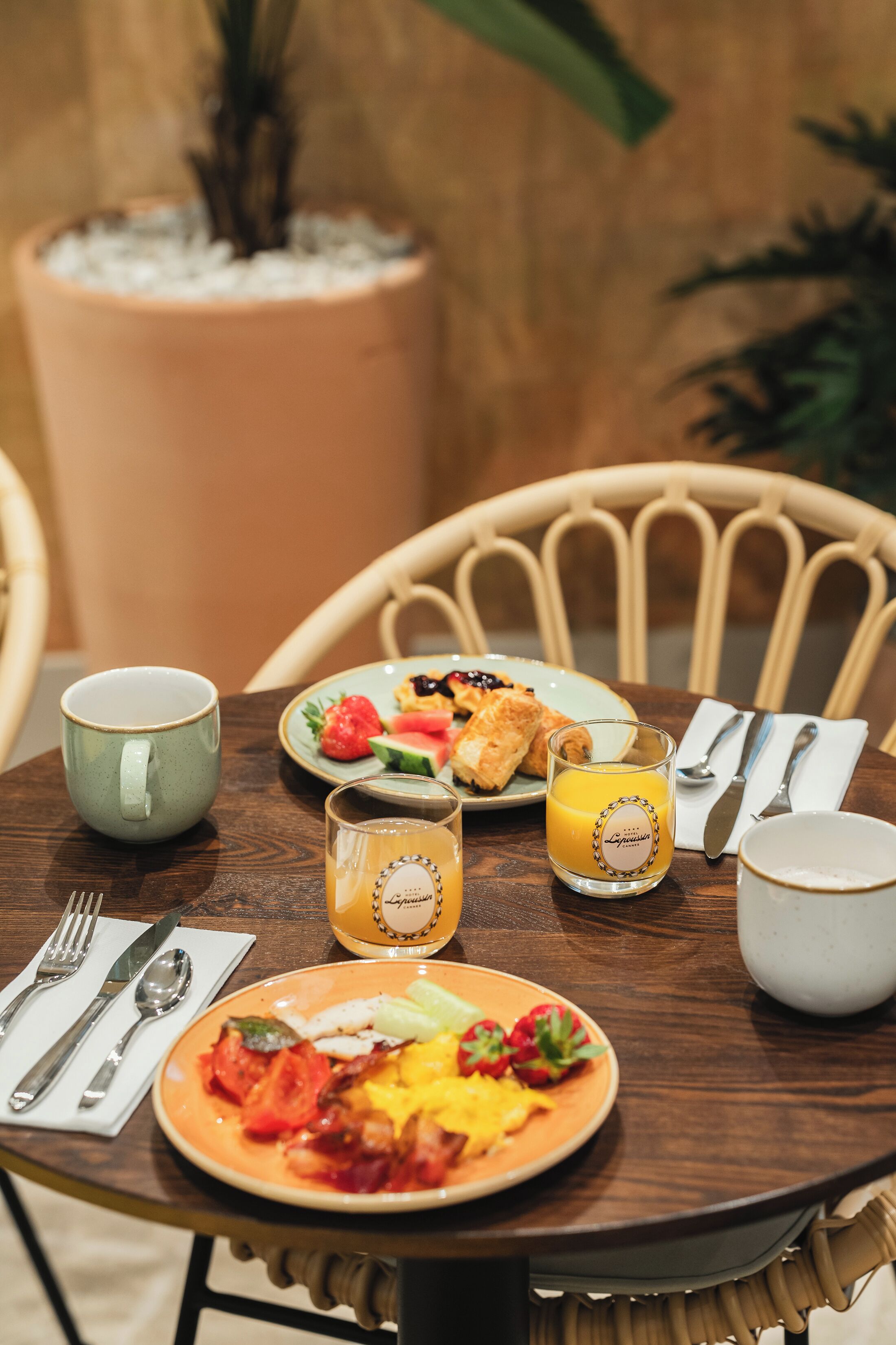 Ein runder Holztisch mit Speisen, einer Tasse, einem Glas Orangensaft und Besteck.