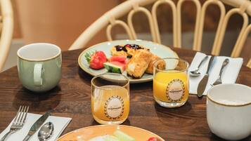 Ein runder Holztisch mit Speisen, einer Tasse, einem Glas Orangensaft und Besteck.