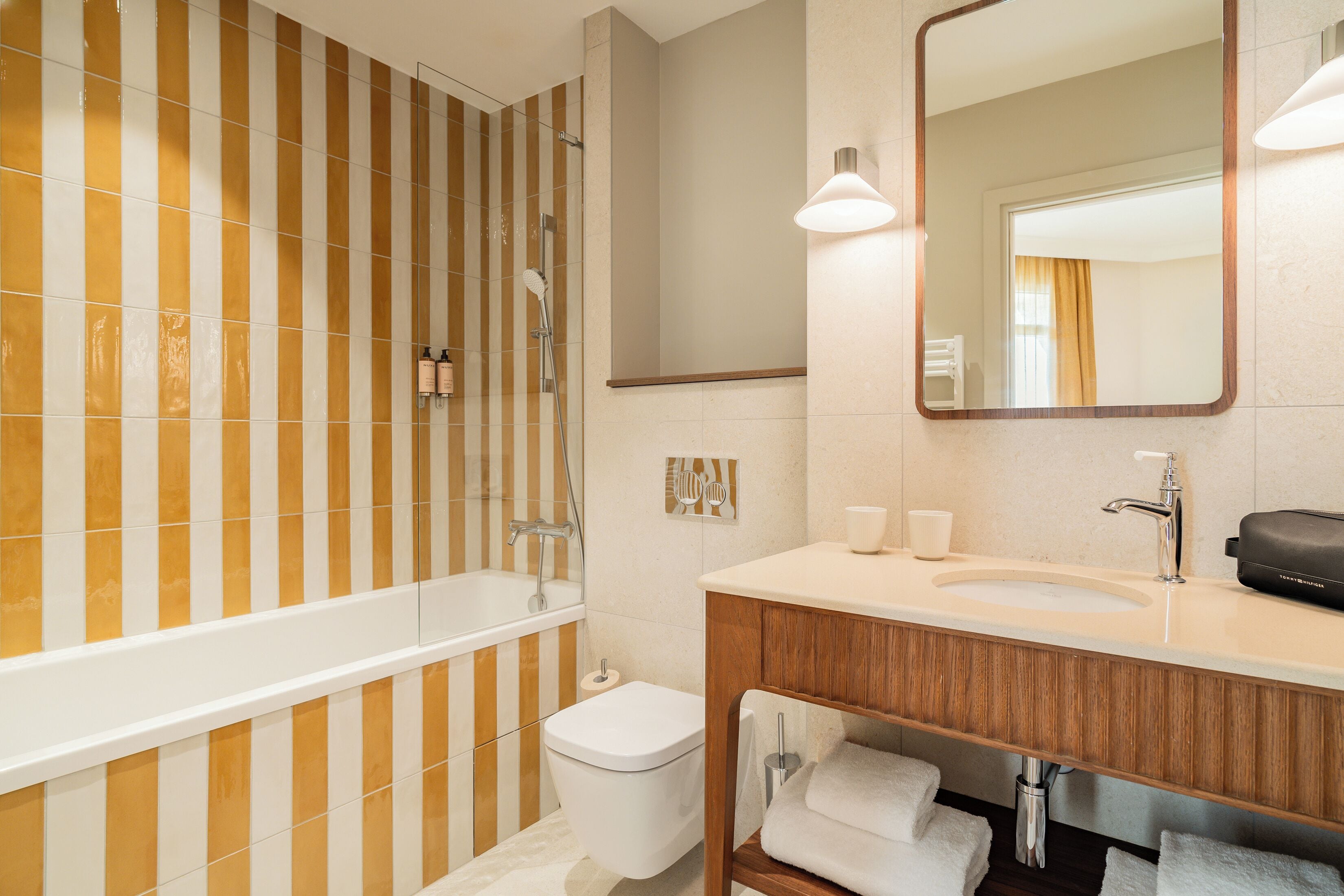 Un baño con bañera, inodoro, lavamanos y espejo.