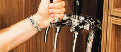 Eine Hand hält ein Glas unter einem Zapfhahn.