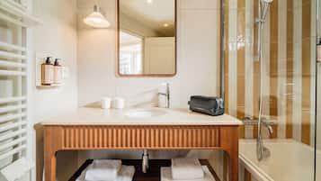 A bathroom with a wooden vanity, a mirror, a sink, a towel rack, and a shower.