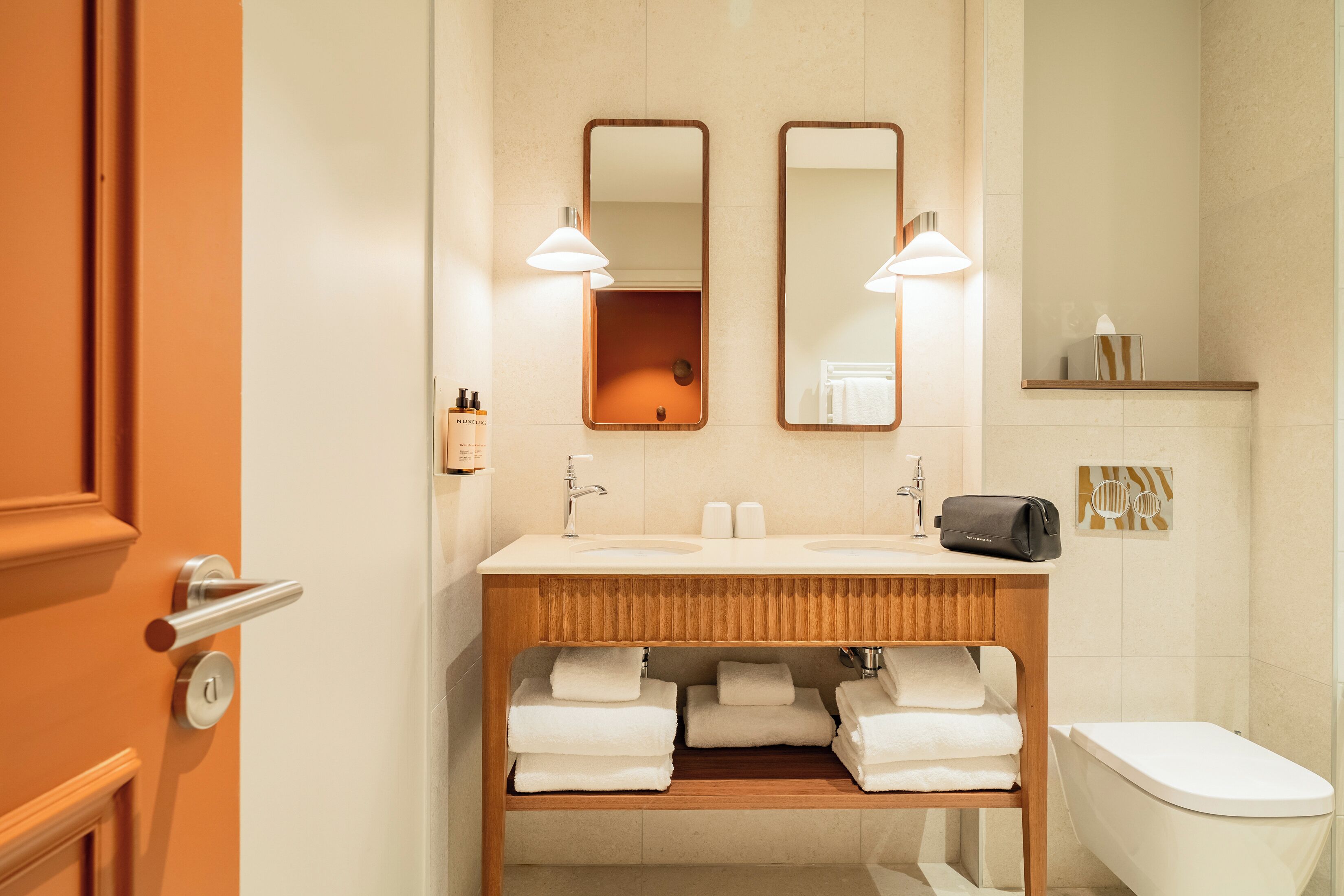 Ein modernes Badezimmer mit zwei Waschbecken, einer Toilette und einem Holzwaschtisch.