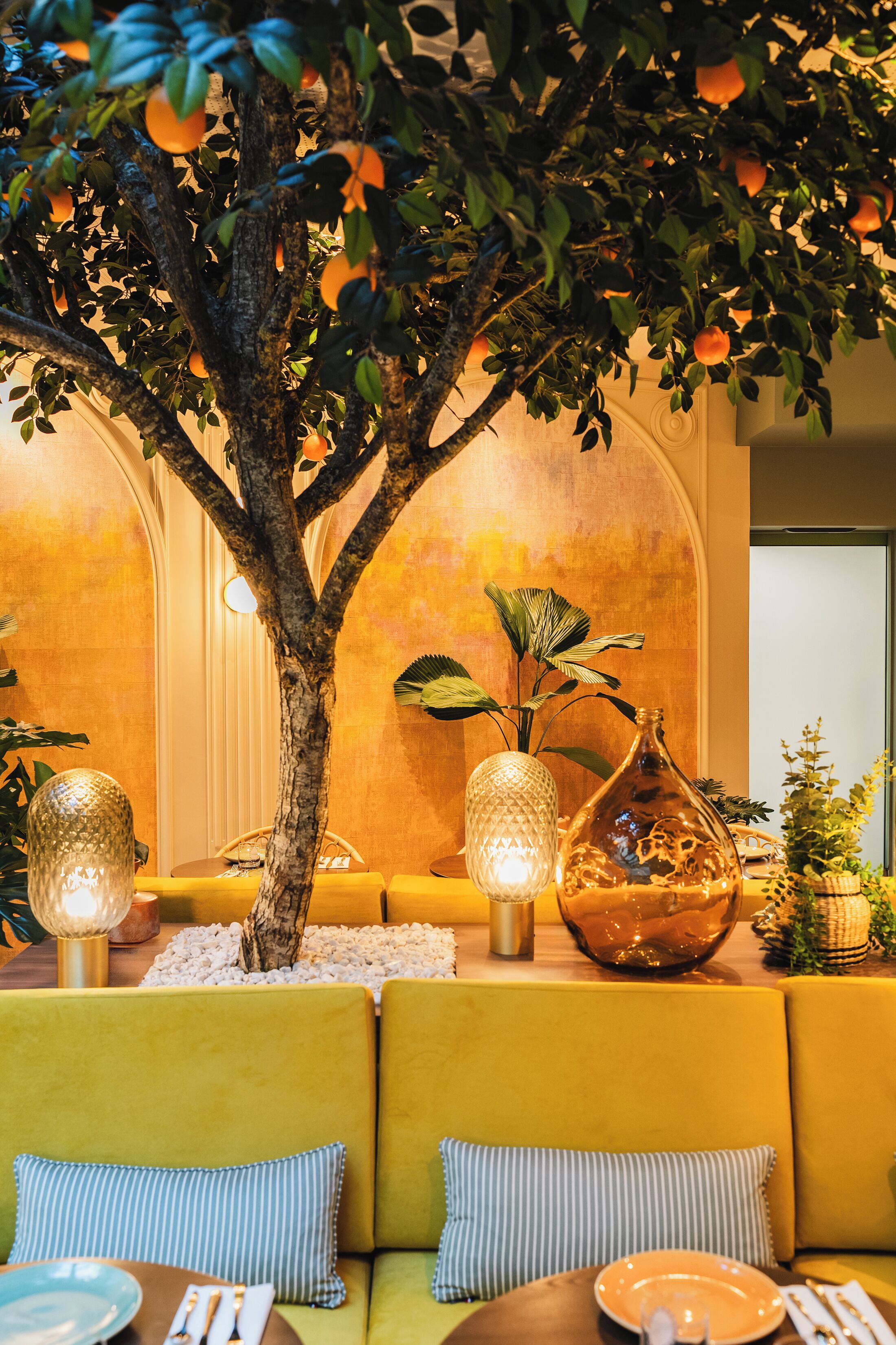 Ein Essbereich mit Baum, gelben Sofas und dekorativen Vasen.