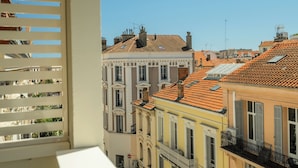 Blick auf mehrstöckige Gebäude mit Balkonen, einem klaren Himmel und einem Fenster mit Rollläden.