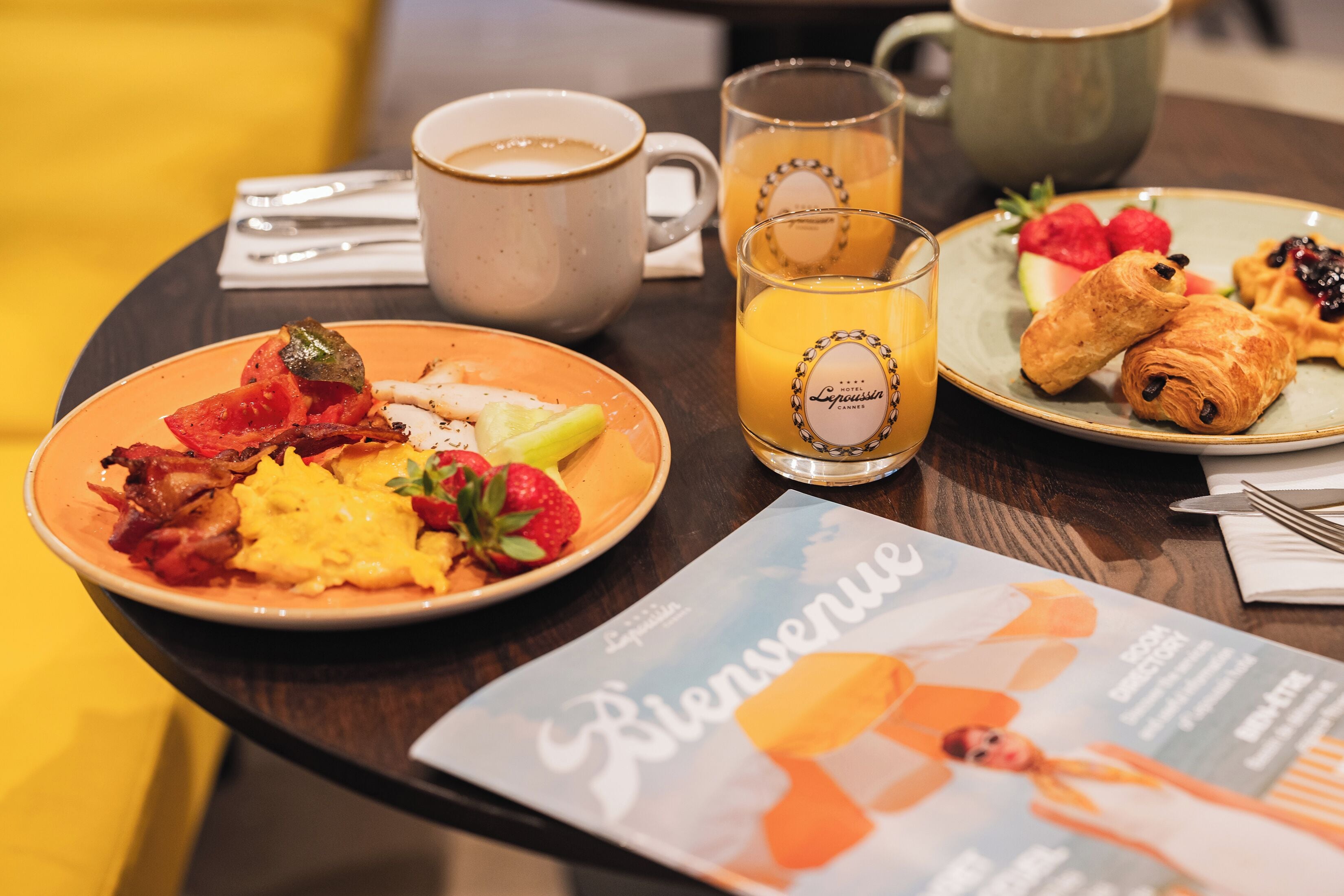 Ett frukostbord med tallrikar fyllda med mat, en kaffekopp, ett glas apelsinjuice och en meny.