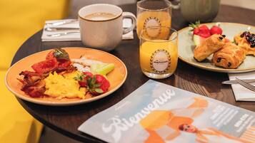 A breakfast table with plates of food, a coffee cup, a glass of orange juice, and a menu.