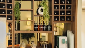 Eine Bar mit Spiegel, Regalen voller Flaschen, einer Kaffeemaschine und einer Pflanze.