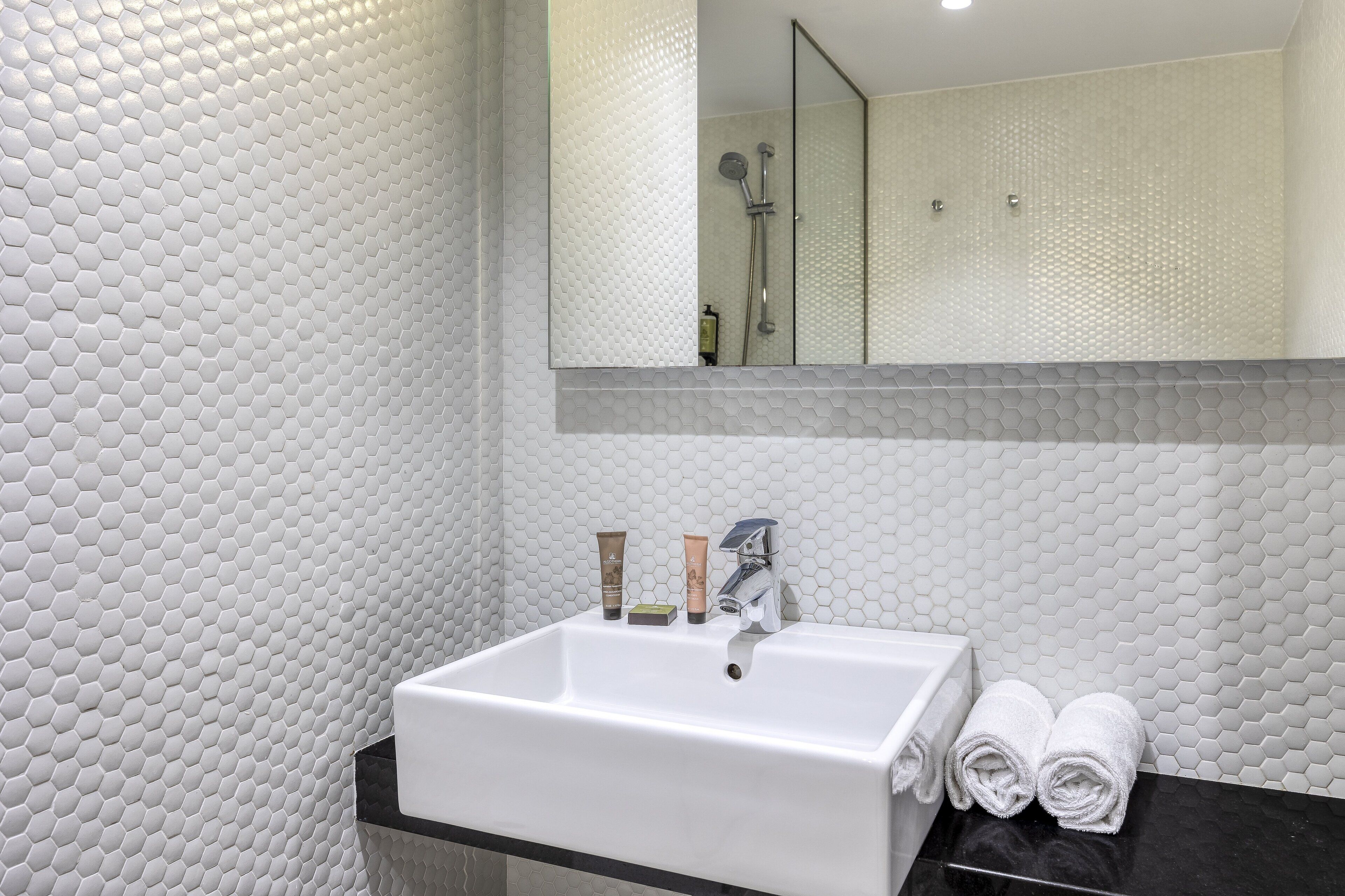 Une salle de bain avec un lavabo blanc, un miroir et une douche.