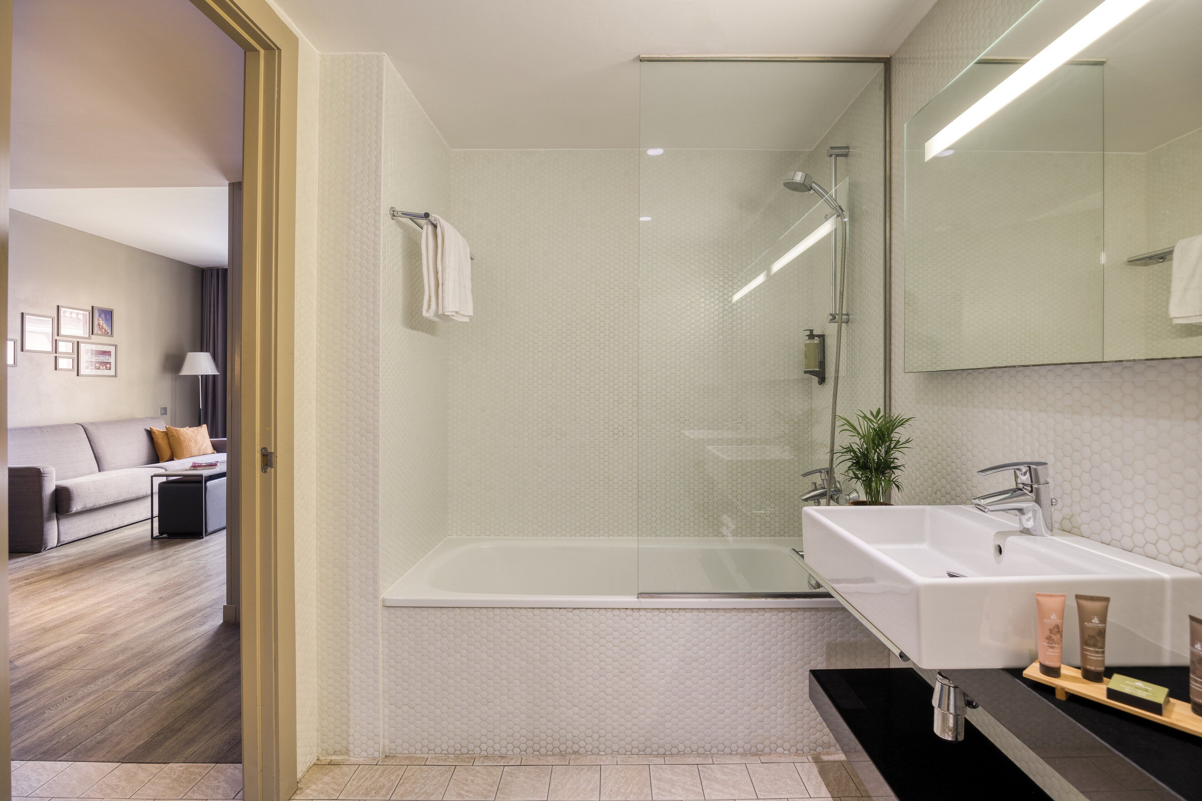 A modern bathroom with a glass-enclosed shower, a white sink, and a large mirror.