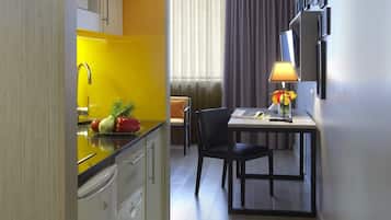 Una habitación de hotel compacta con cocina, comedor y un gran ventanal con cortinas.