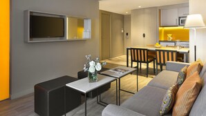 A modern living room with a sofa, a coffee table, and a TV mounted on the wall. - Citadines Ramblas Barcelona (Barcelona)