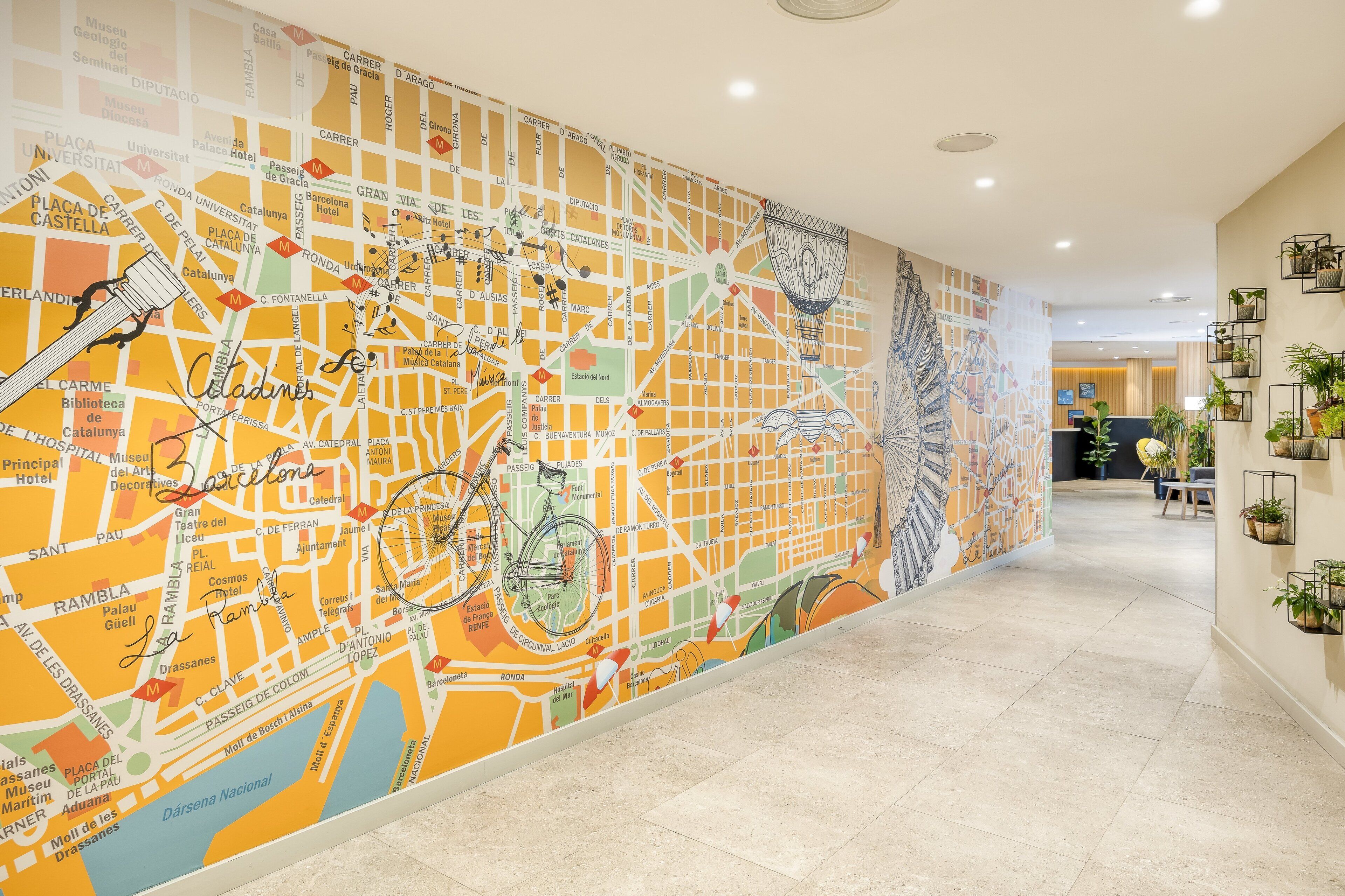 Un couloir orné d’une grande fresque murale colorée représentant une carte, avec un vélo et une fontaine.