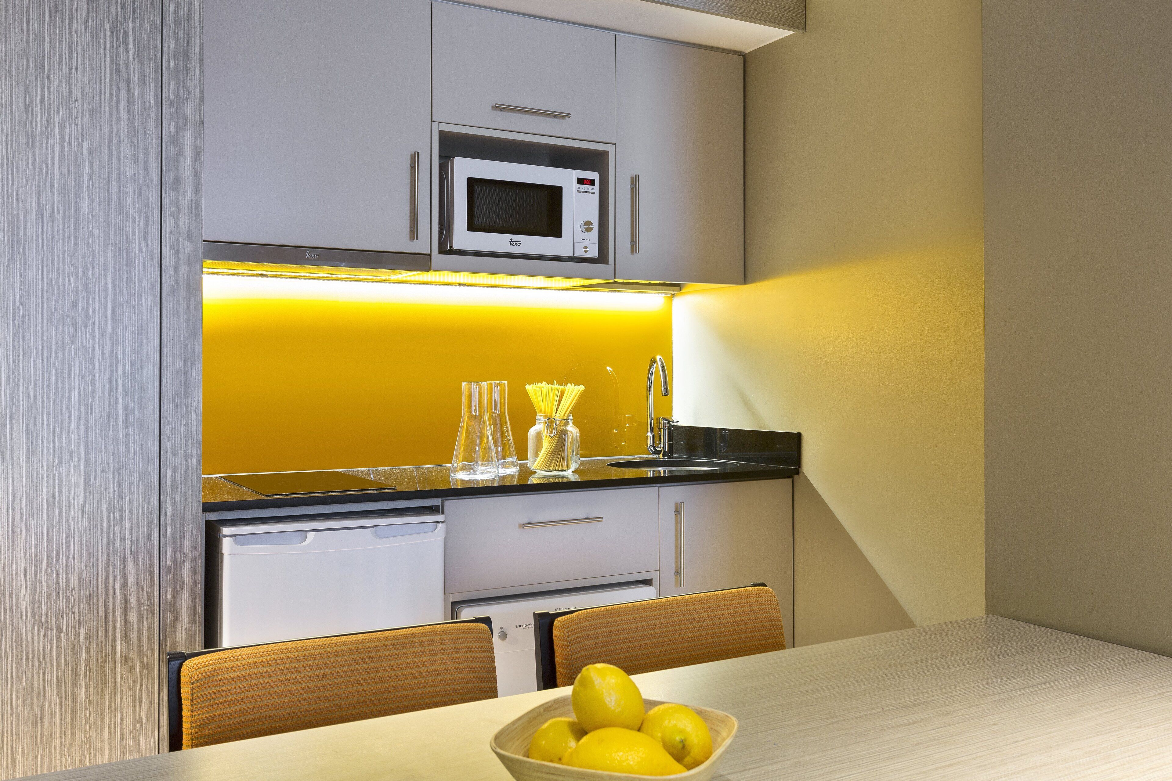 Une cuisine moderne équipée d’un four à micro-ondes, d’un évier et d’une table à manger avec des chaises.