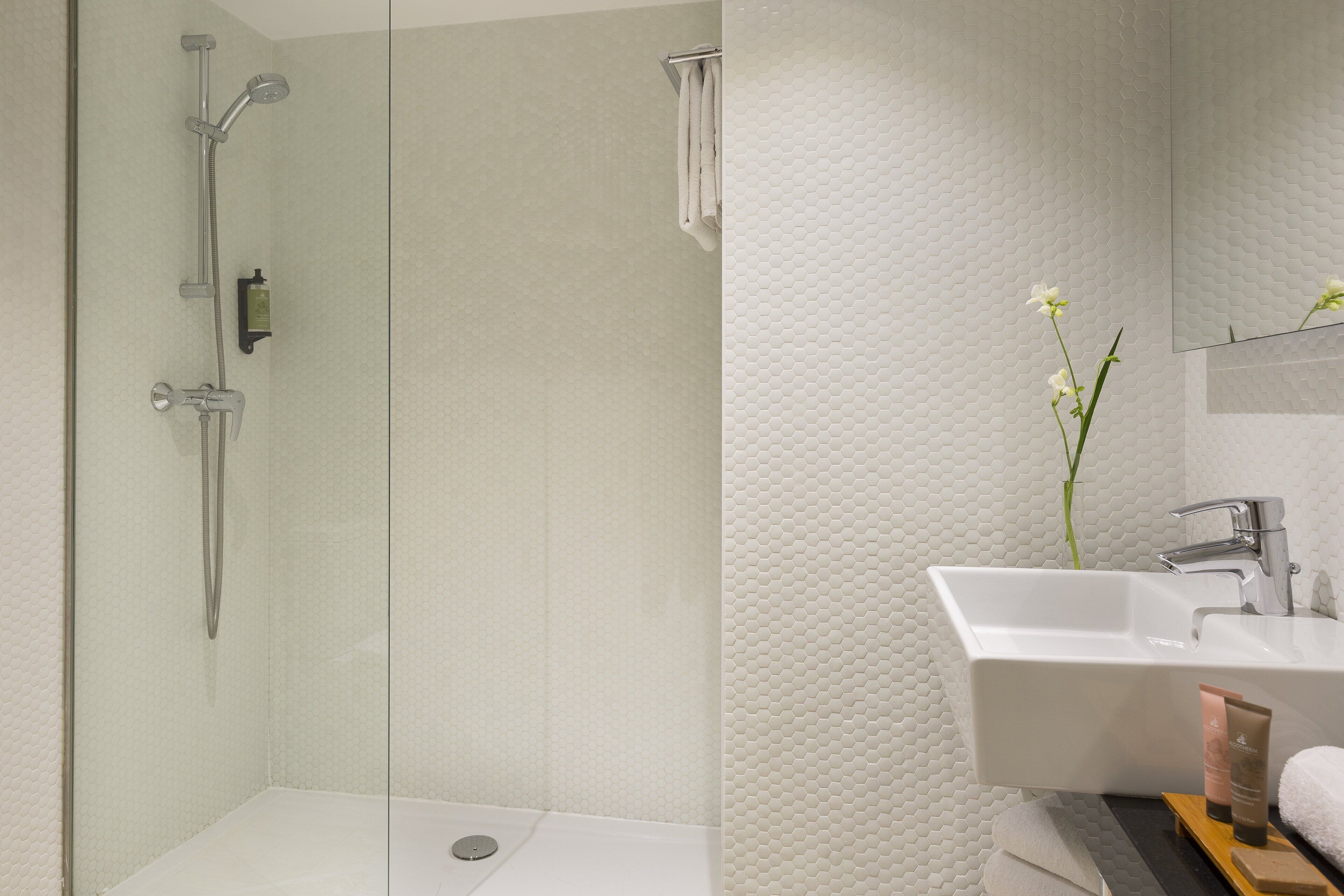 A modern bathroom with a glass-enclosed shower, a white sink, and a mirror above it.