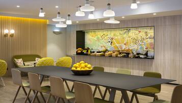 A modern dining area with a long table, green chairs, and a bowl of lemons.